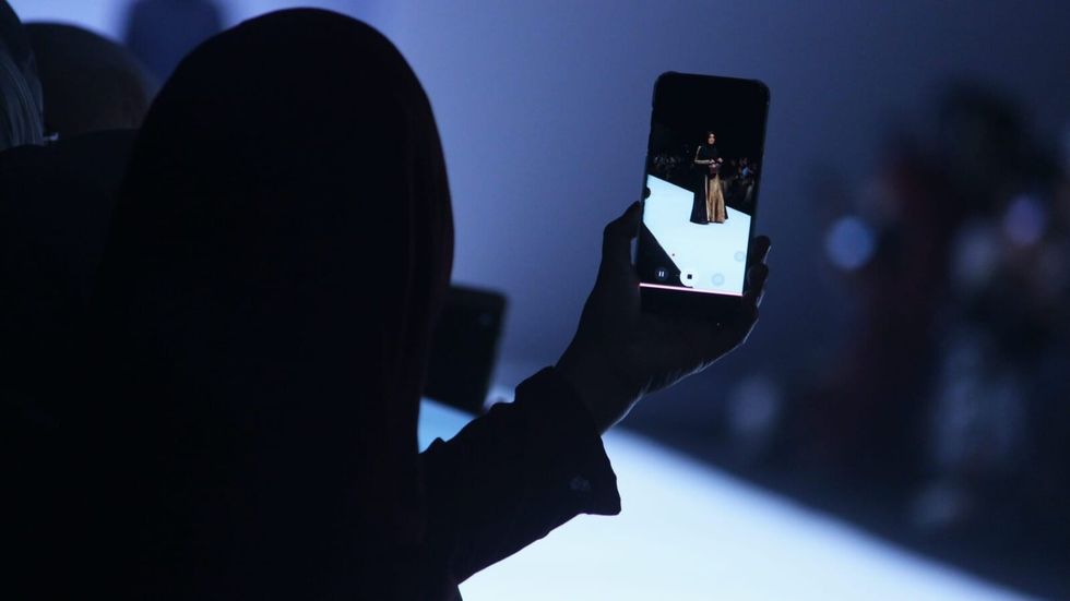 person taking video of model on the runway