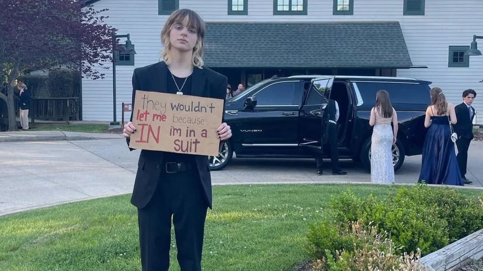person wearing a black suit and holding a sign