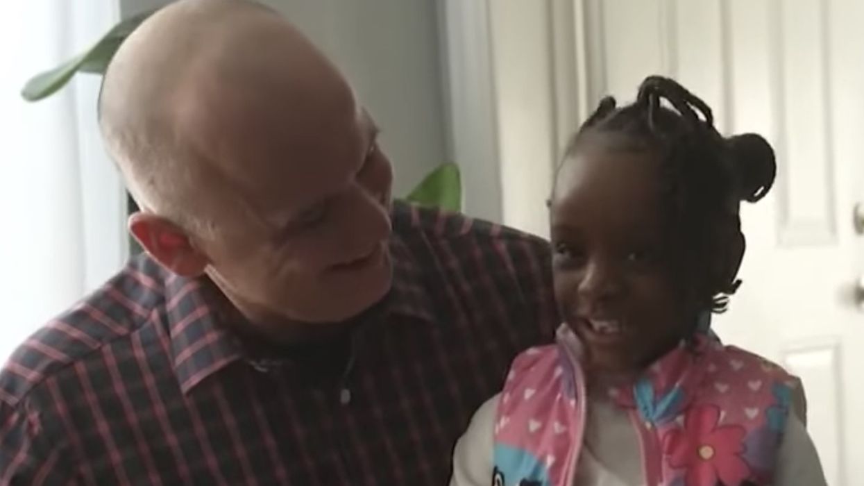 Police officer looks at little girl sitting near him.