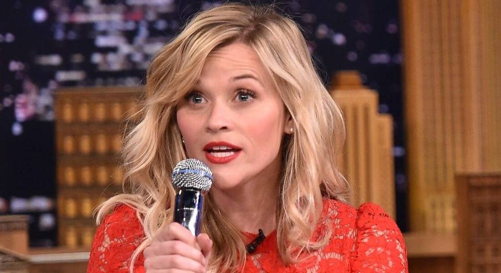 Reese Witherspoon in red dress talking into a microphone.