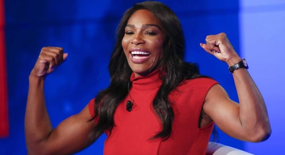 Serean Williams in a red dress with fists in the air of strength.