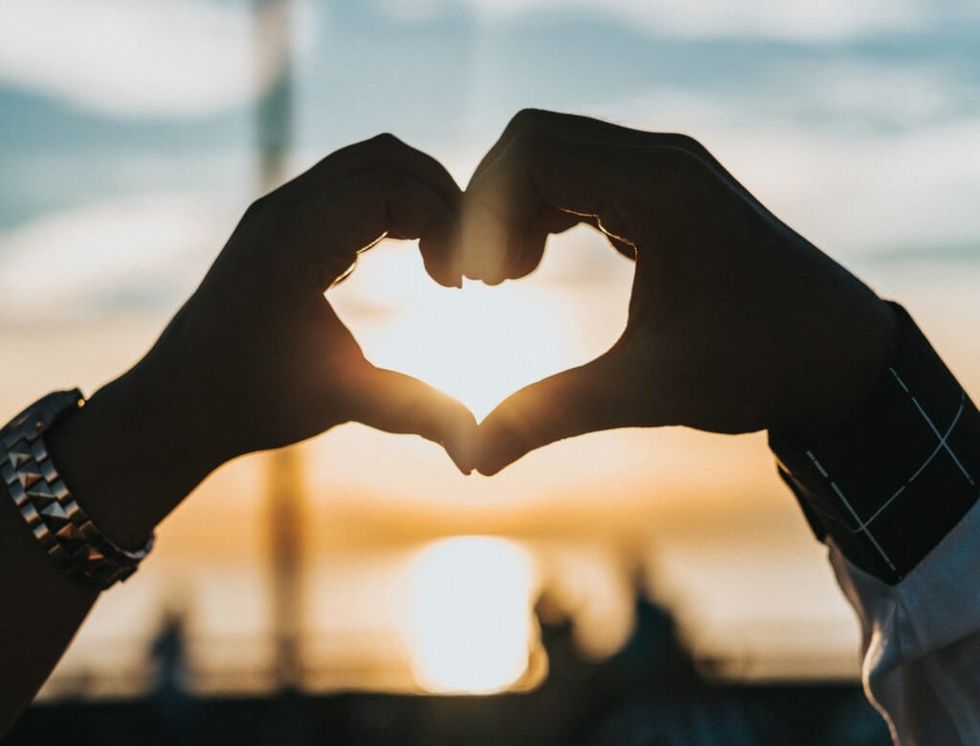 silhouette of two hands making a heart