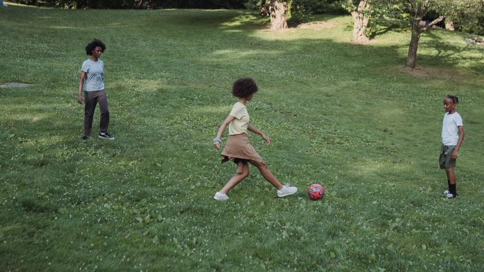 three children playing football outside