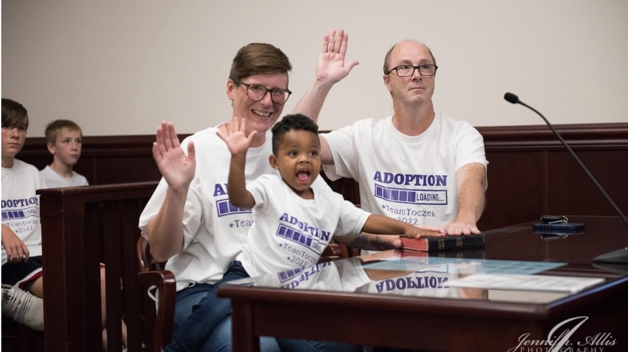Two adults and one kid raising their hand.
