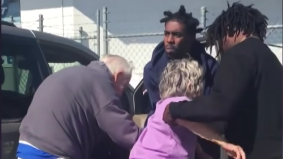 two men in black hoodie's helping an elderly couple
