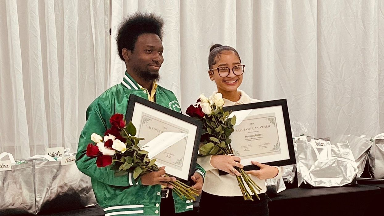 Two people holding framed certificates and a bouquet of flowers.
