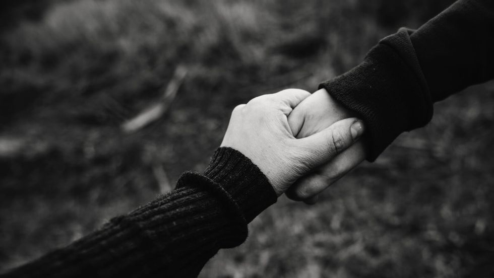 two people wearing black outfits holding hands