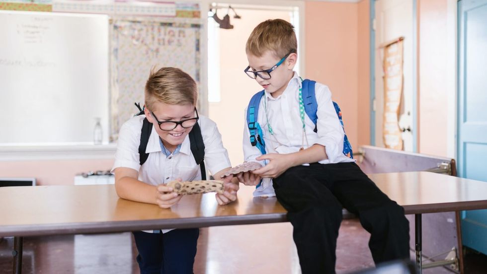 two school boys sitting on a desk