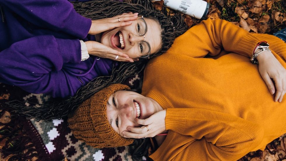 two women laying on fallen leaves