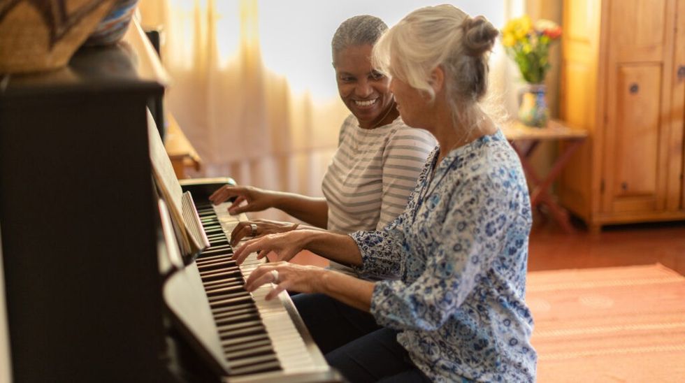 two women play piano together