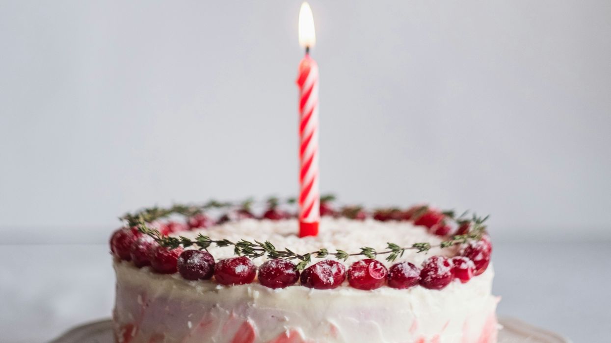 White and pink covered cake with lightened candle.