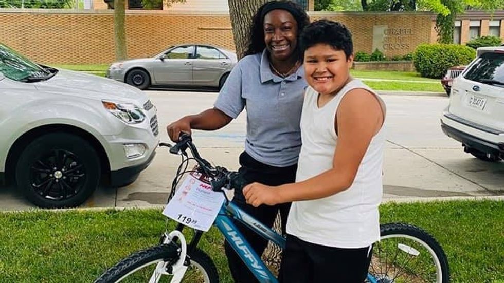woman and a little boy standing with a bike