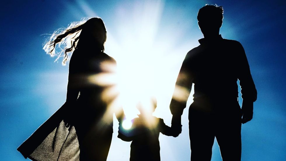 woman and man holding a little child's hands