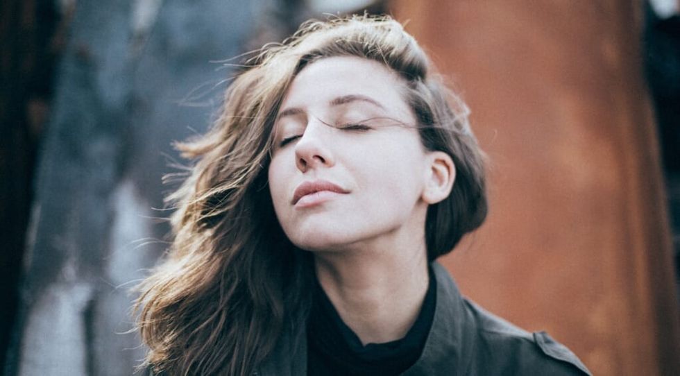 woman closes her eyes outside