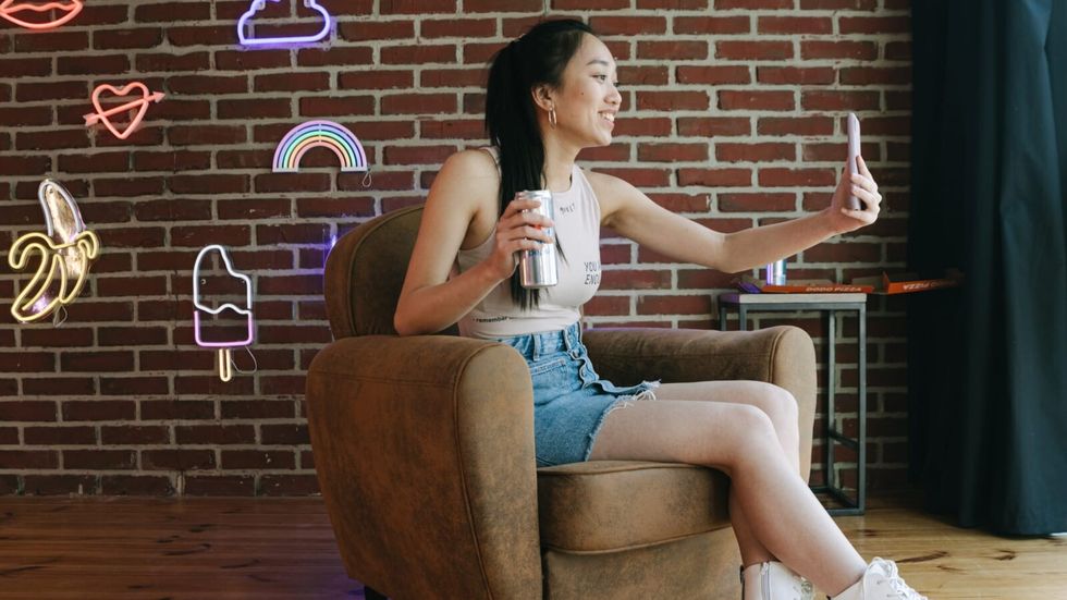 woman holding a phone, sitting in a sofa in front of a brick wall