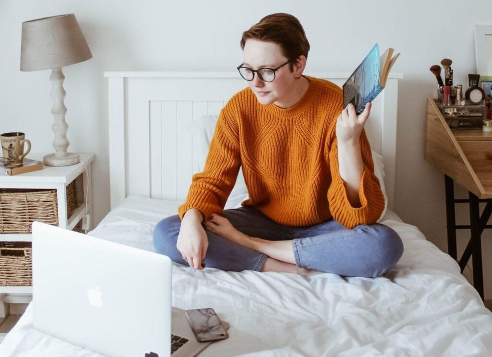 woman-holding-book-while-working-bed
