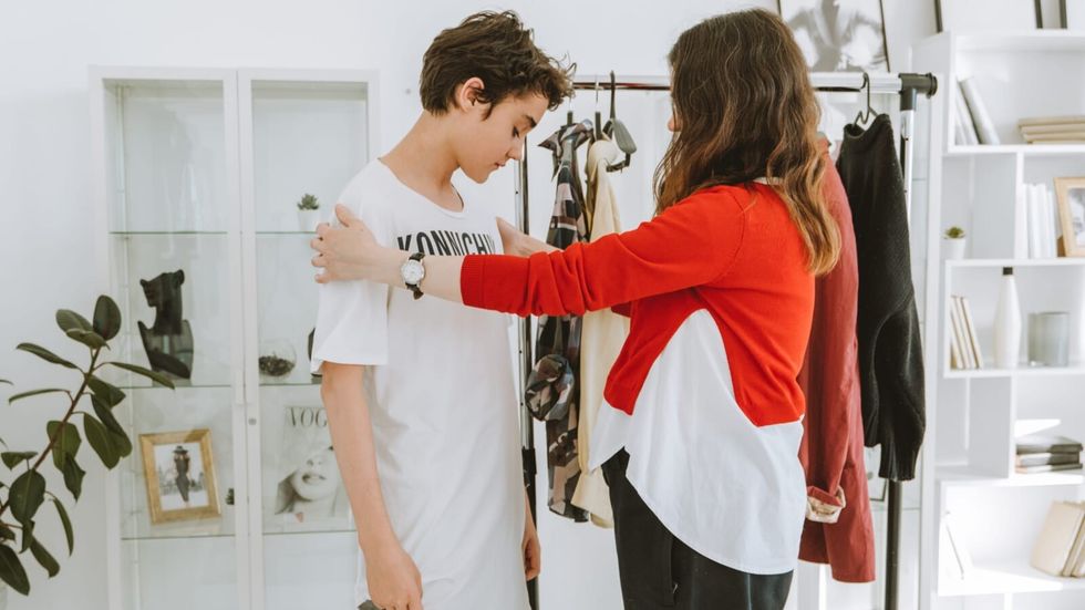 woman in red and white outfit holding shoulders of boy in white tshirt
