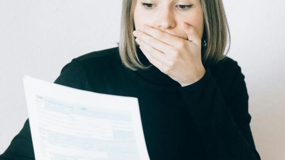 woman looking shocked reading a paper