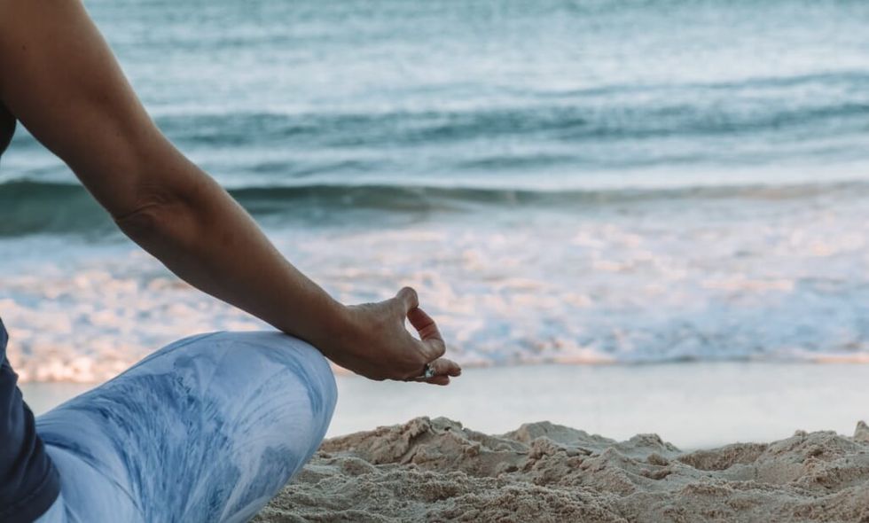 woman meditates on the beach on a beautiful day