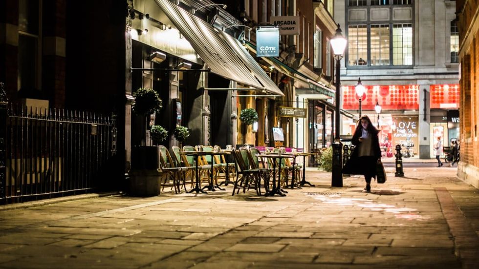 Woman on a phone walking down an empty city street with a lone restaurant