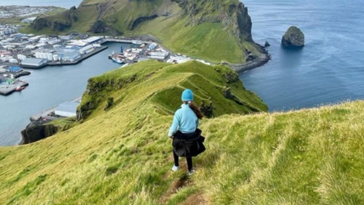 Woman running down a green hill.