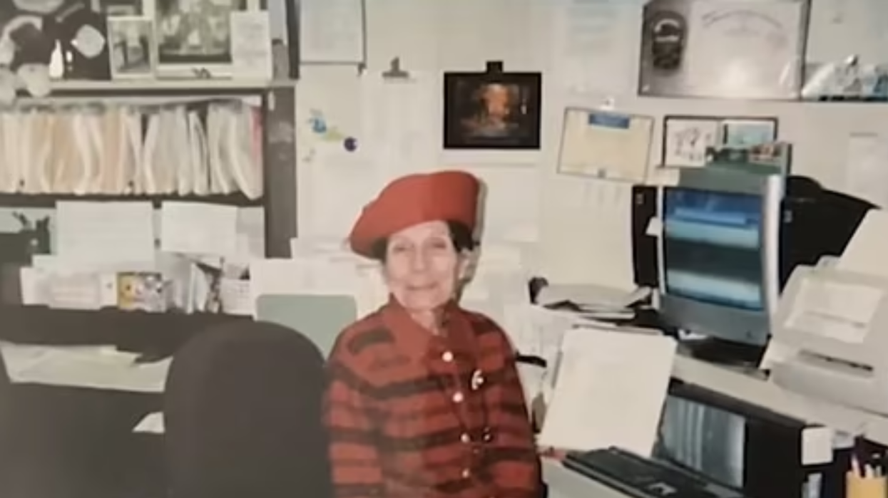 Woman sitting in a chair, wearing a red outfit and a red hat.