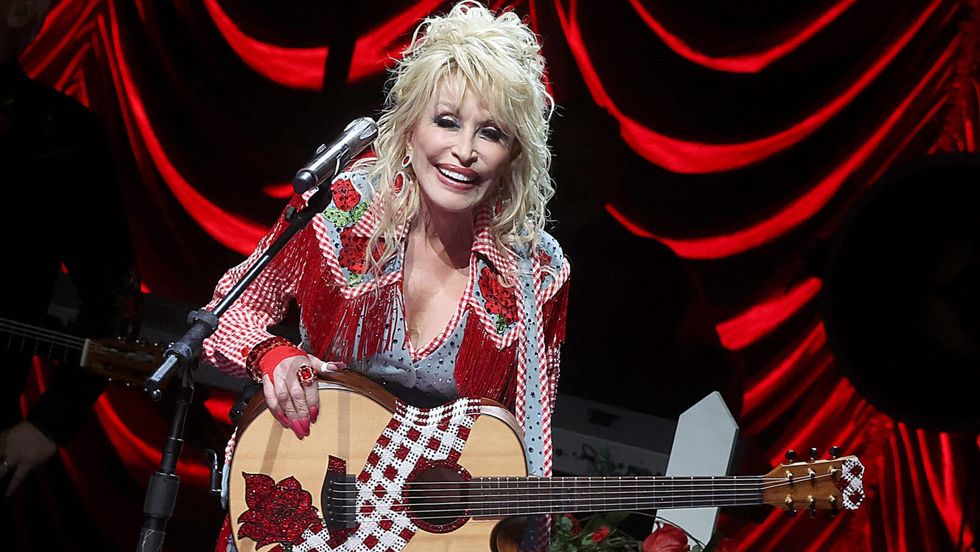 woman smiling and holding a guitar on stage