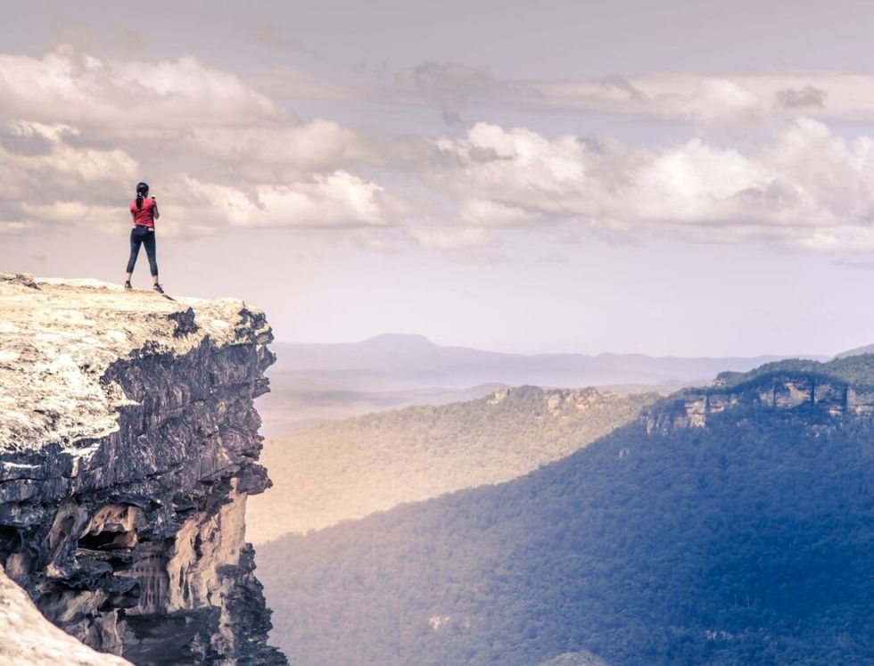 woman-standing-top-tall-mountain-feeling-free