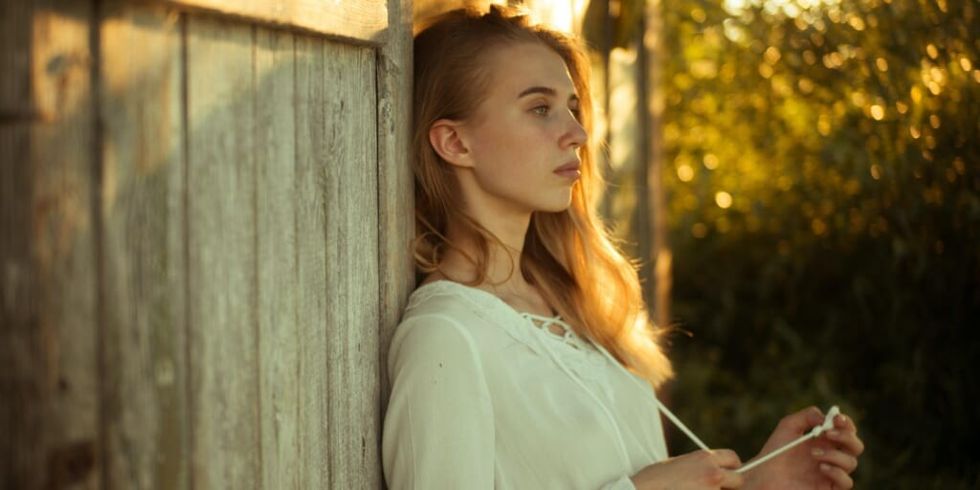 Woman wearing white top leaning on wooden wall by Masha Raymers on Pexels