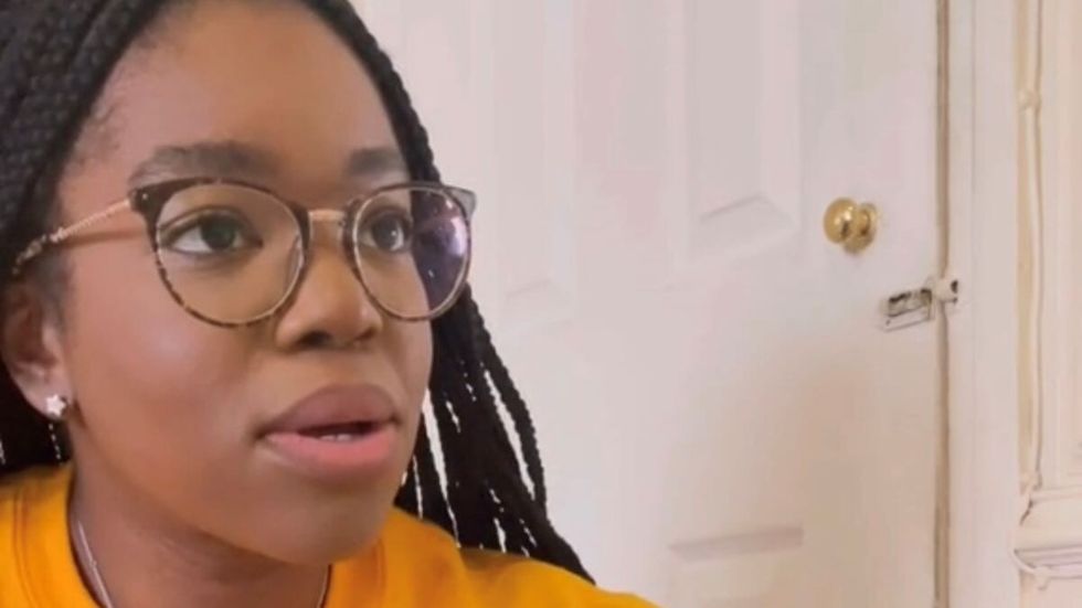 woman with black hair and glasses wearing a yellow shirt