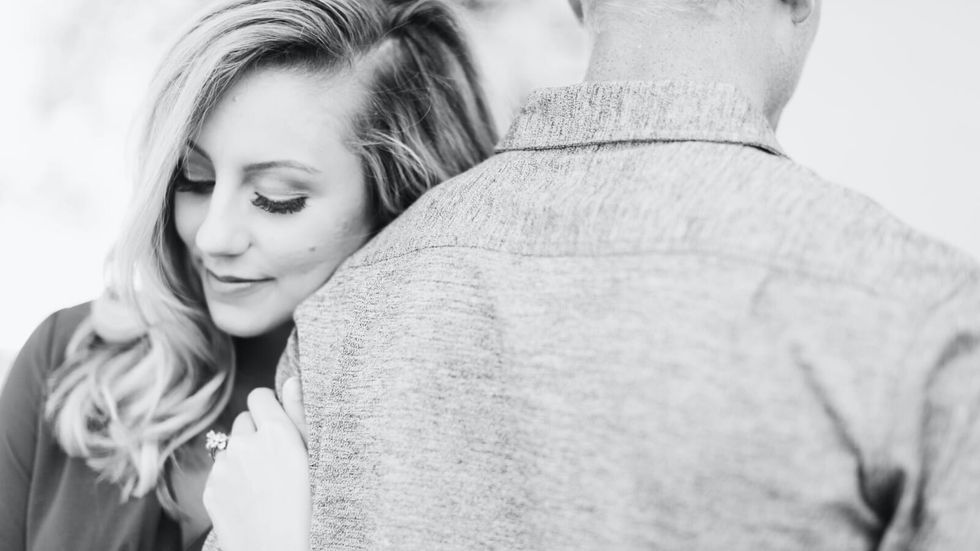 woman with engagement ring holding on to a man's arm