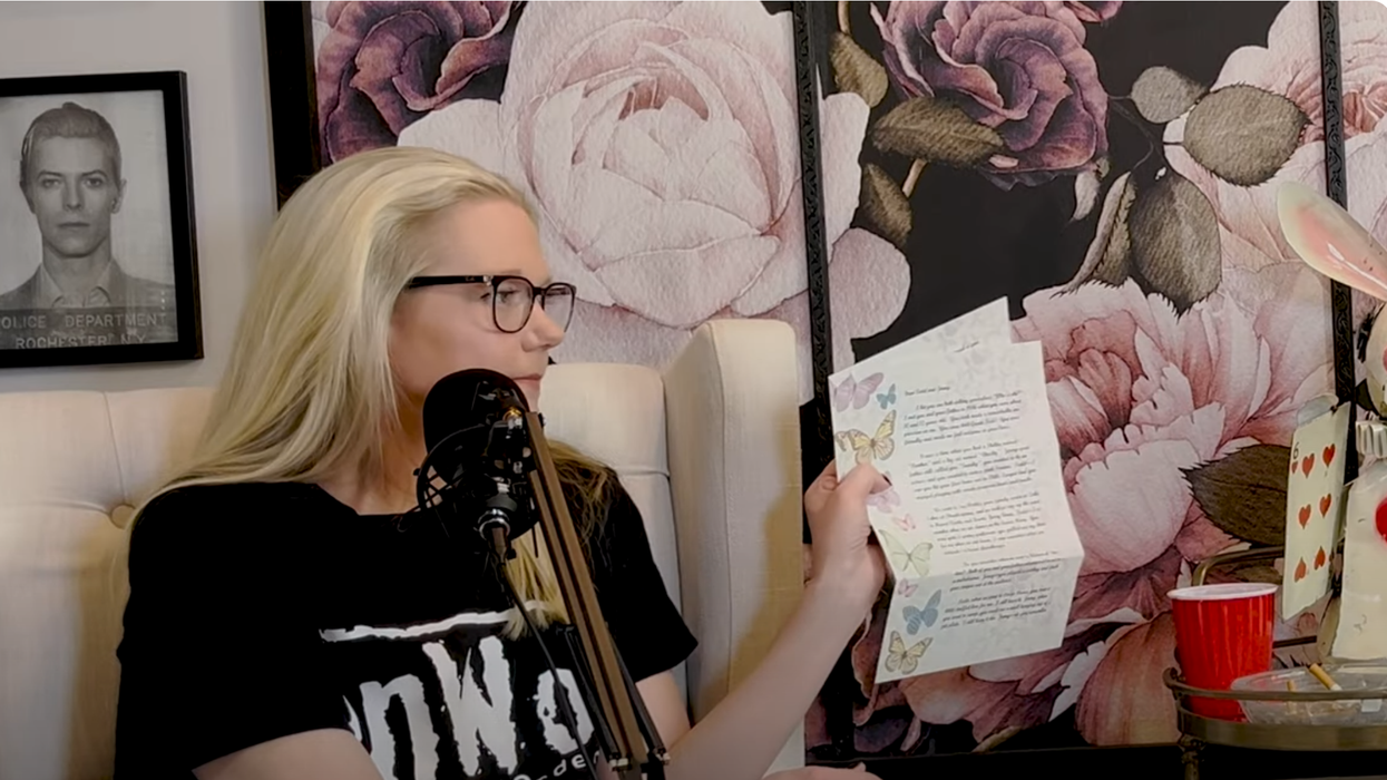 Woman with glasses holding a letter.