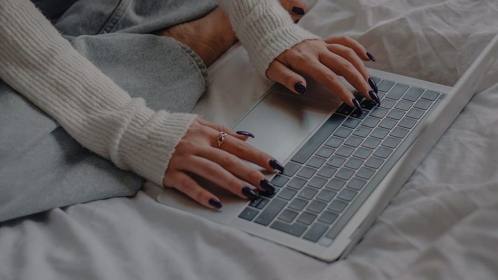 woman woking on laptop on her bed