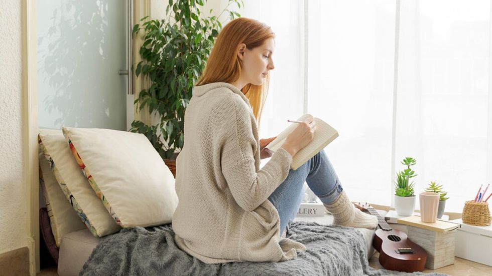 woman writing in diary on her bed
