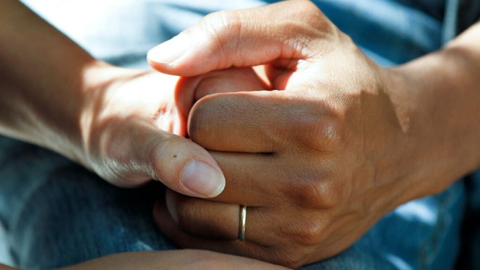 Women holding hands in hospital bed