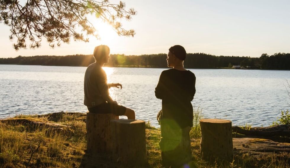 young people having a chat by the lake on sunny day