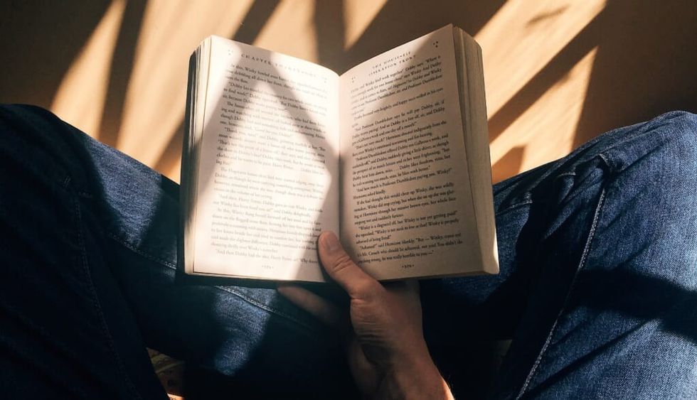young person sits on the floor reading a book