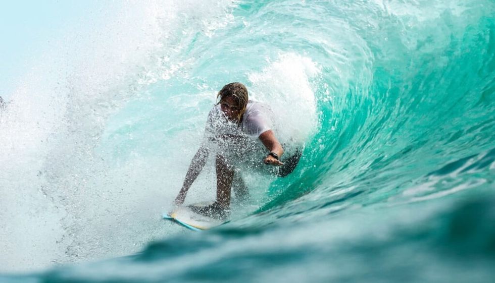 young person surfing engulfed by water