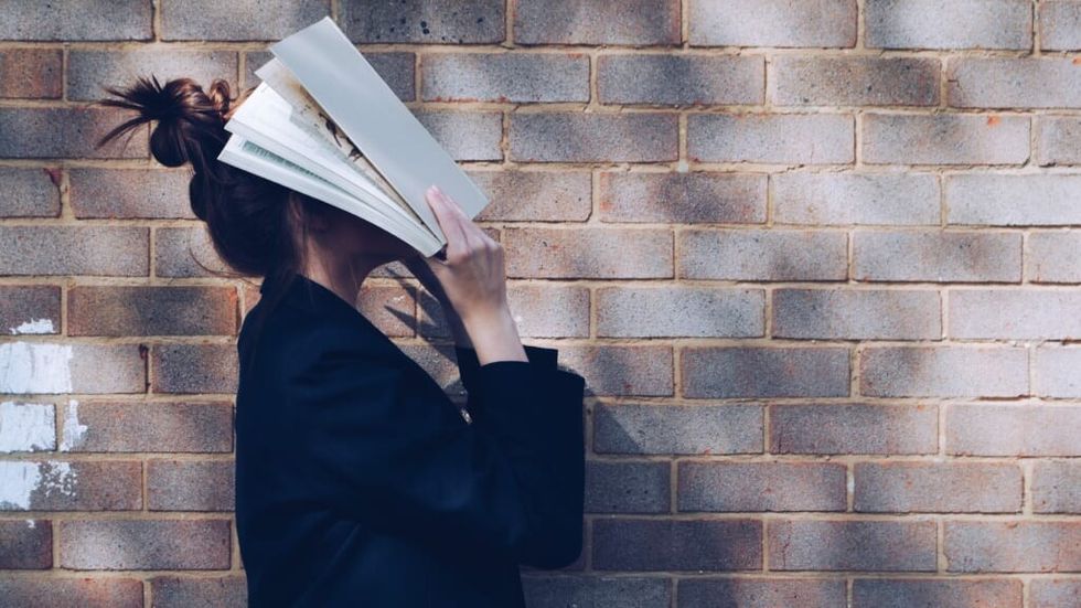 young woman has books on her face troubled