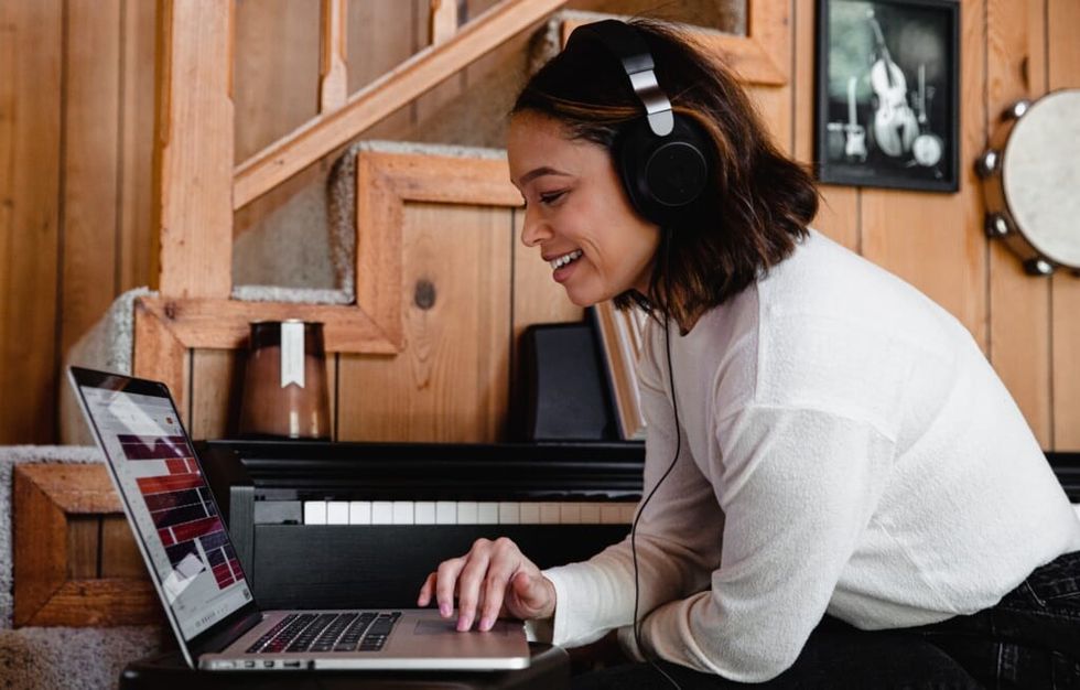 young woman listens to music while on laptop