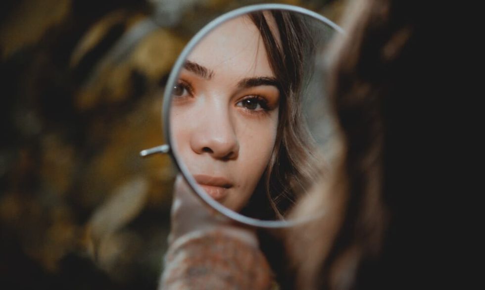 young woman reflecting looks in mirror