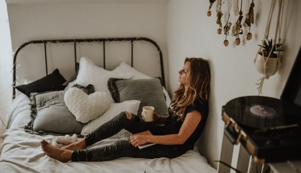 young woman sits on bed