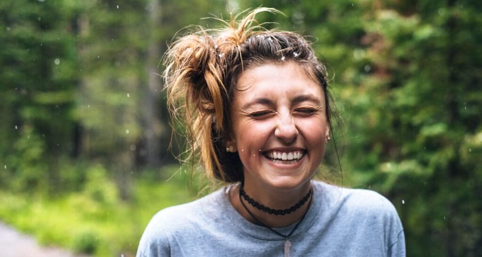young woman smiling amongst greenery