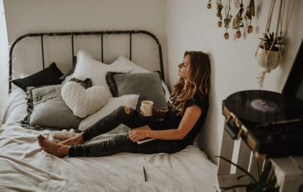 young woman stuggles with stress sitting on bed