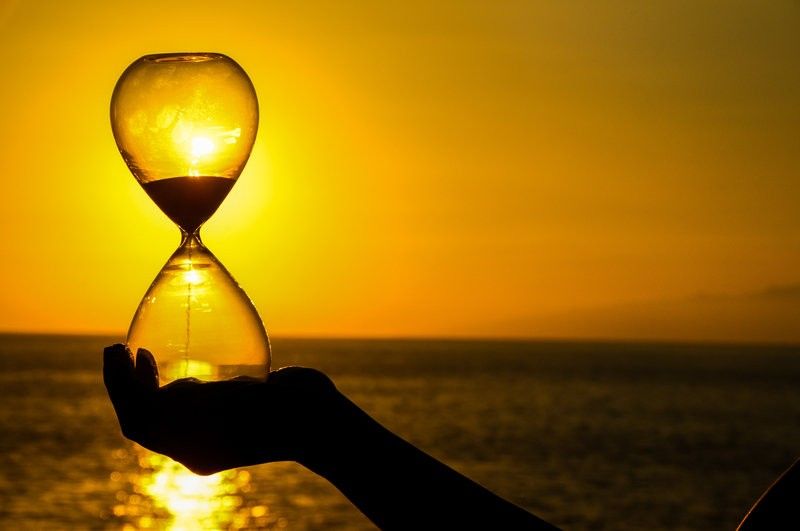 woman holding an hourglass over the sun showing time