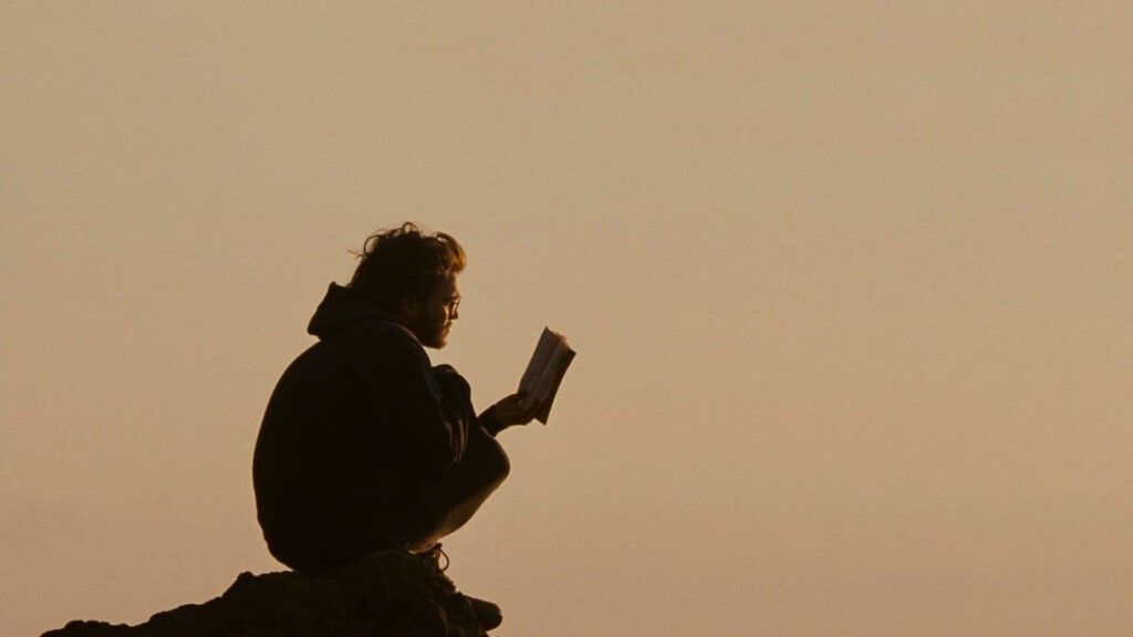 man reading book at sunset how to read more often
