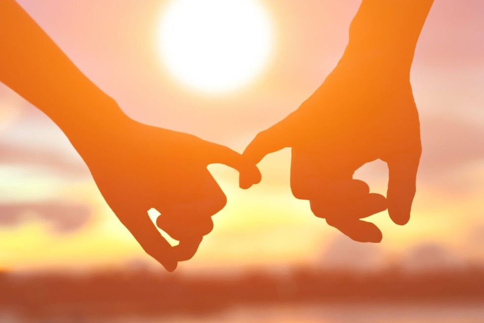 Silhouette of hands interlocked at sunset
