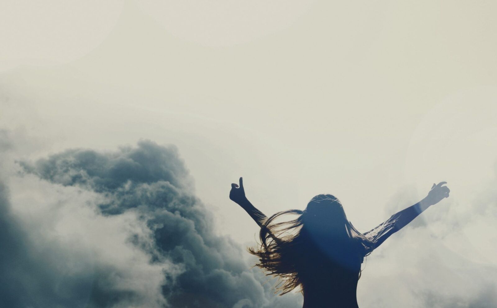 woman-facing-clouds-hands-up