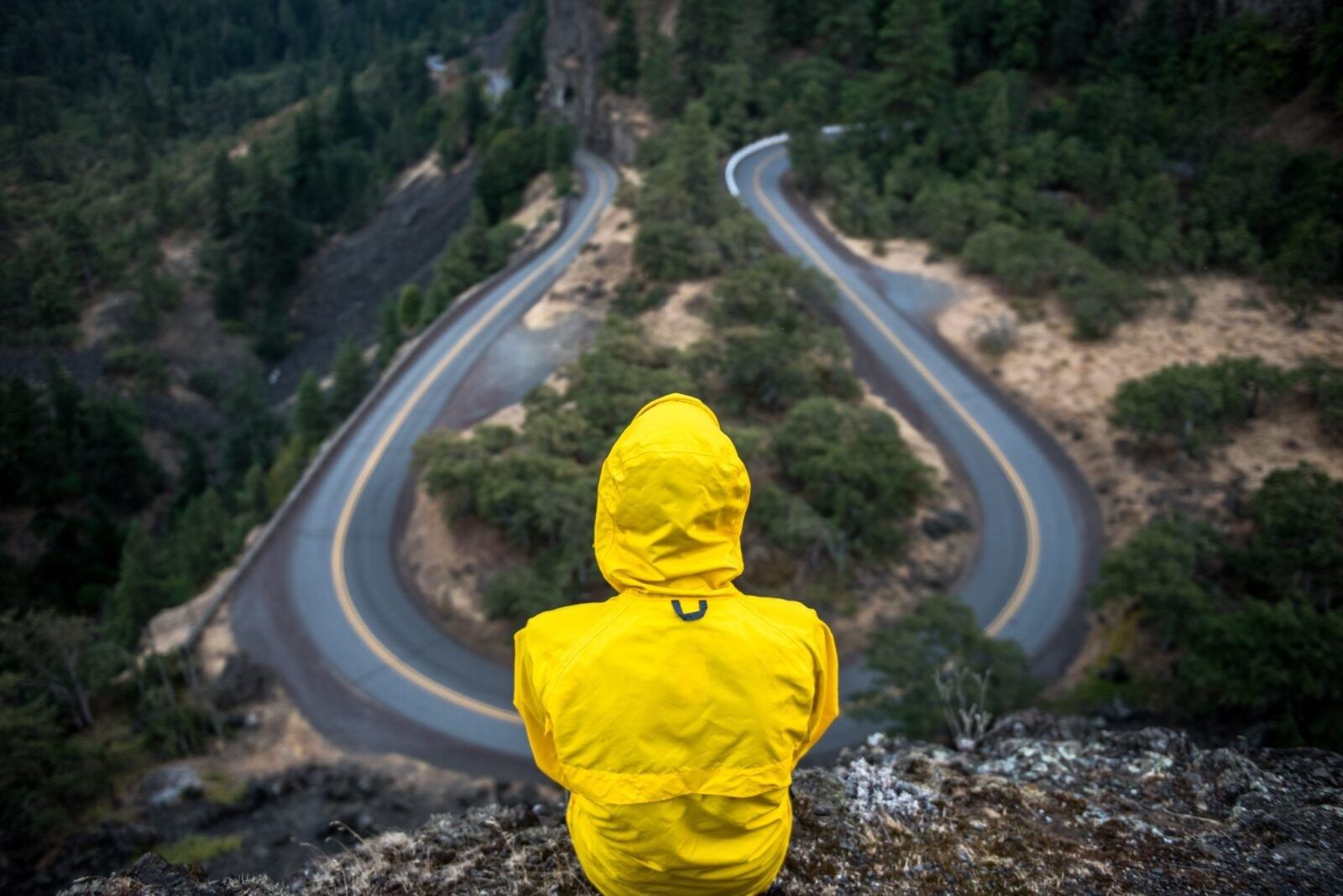 Man-in-yellow-jacket-looking-down-at-winding-road