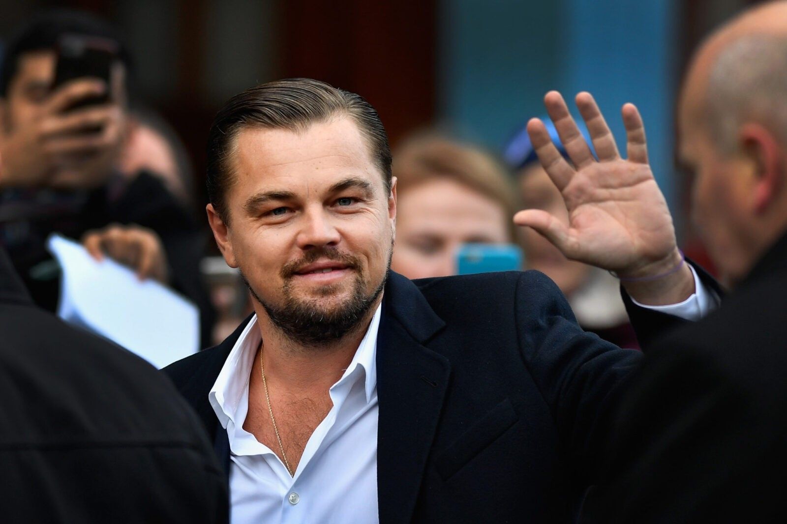 Leonardo Di Caprio in white shirt waving to fans.